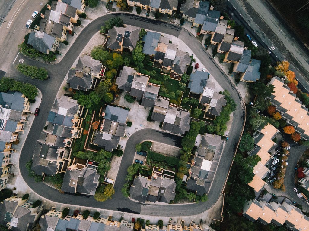 Aerial view of a modern neighborhood with roads and buildings in a lush urban setting.
